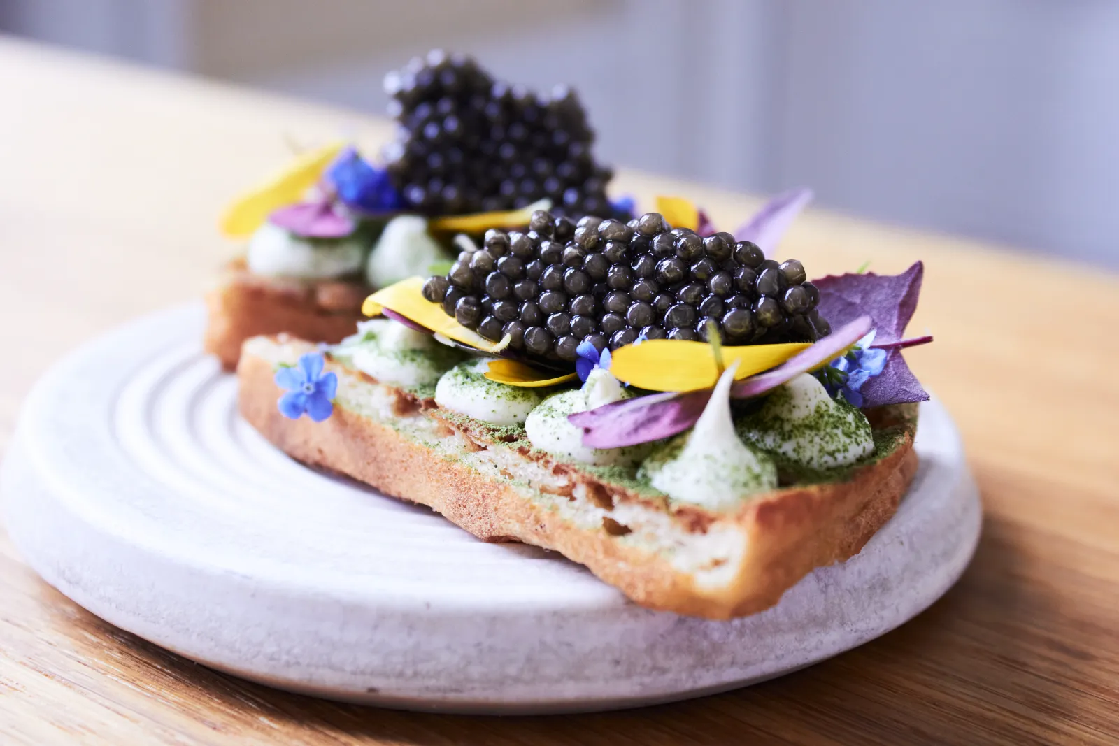 Antonius Caviar served on toast with herb cream and edible flowers in a Nordic kitchen
